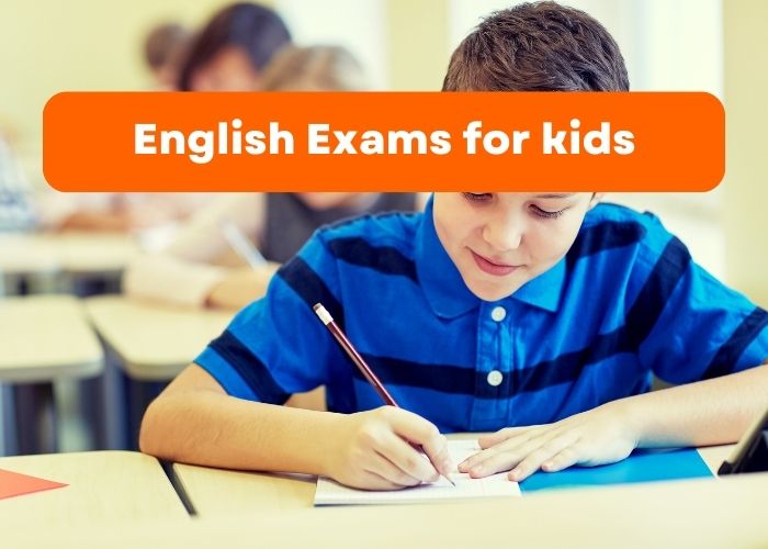 A very young boy who is wearing a striped blue and dark blue T-shirt sitting at his desk writing some notes in English.